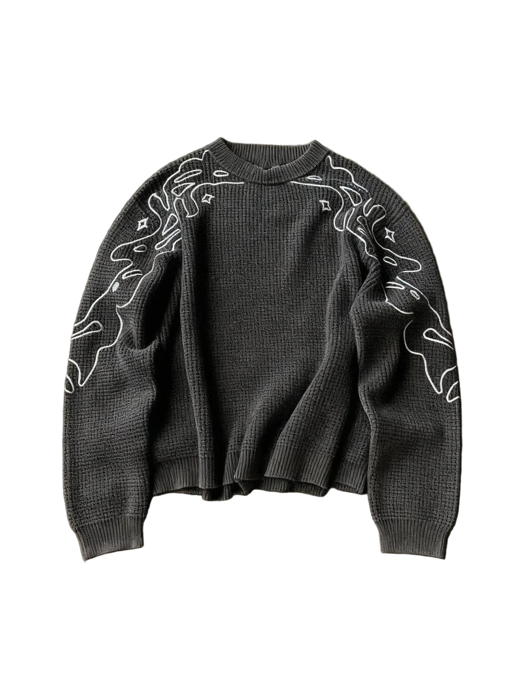 Dark gray sweater with white abstract patterns on a brown textured surface