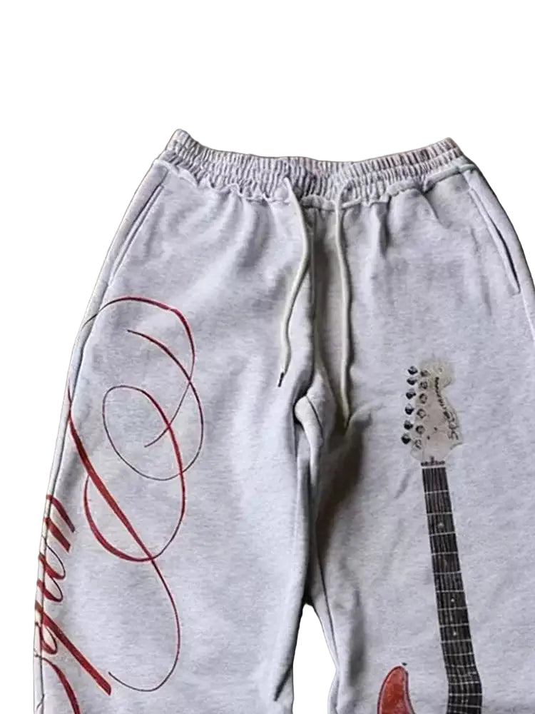 Gray sweatpants with red and black guitar design on a concrete floor
